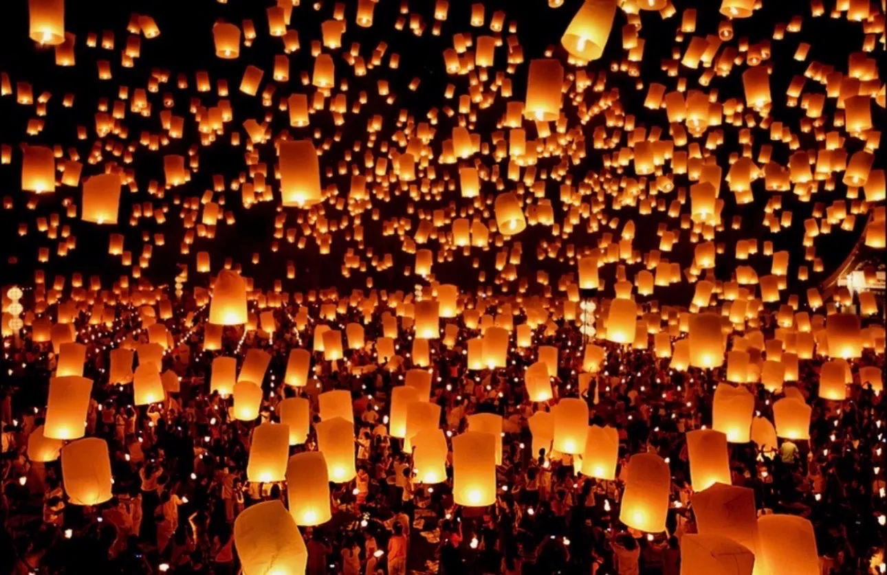 Many paper lanterns rising into the night sky